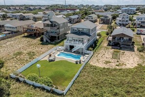A residential area with houses, a swimming pool, and a fenced yard. - Drift | 650 ft. to the beach | Private Pool, Hot Tub (Kitty Hawk)