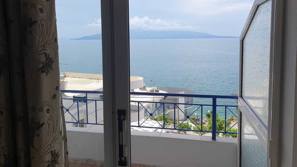 Un balcón con vistas al mar y montañas a lo lejos.