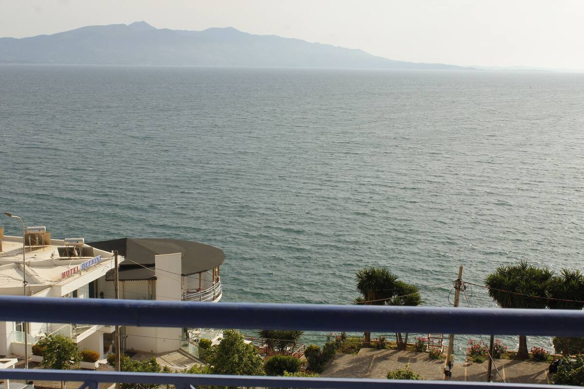 A hotel with a view of the sea and mountains in the background.