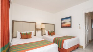 A hotel room with two beds, each with a striped blanket and pillows, a large mirror, and a painting on the wall. - Beach Front Villa Diamante at Tesoro Ixtapa (Ixtapa Zihuatanejo)