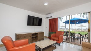 A living room with a TV, a wooden cabinet, and orange chairs. - Beach Front Villa Diamante at Tesoro Ixtapa (Ixtapa Zihuatanejo)