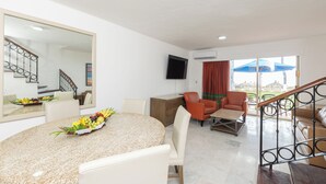 A hotel room with a dining area, a living room, a staircase, and a balcony with an umbrella. - Beach Front Villa Diamante at Tesoro Ixtapa (Ixtapa Zihuatanejo)