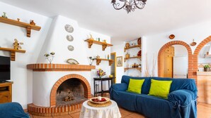 Een gezellige woonkamer met een open haard, een blauwe bank en houten planken met decoratieve objecten.