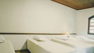 Two single beds with white linens and pillows, a bedside table, and a window.