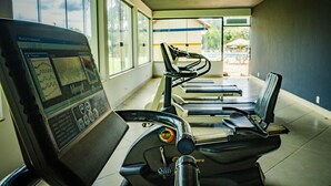 A gym with treadmills and exercise equipment, large windows, and a view of the outdoors. - Hotel Fazenda Ramon (Sao Lourenco)