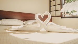 A bed with a heart-shaped towel arrangement and a window with a view of greenery. - Hotel Fazenda Ramon (Sao Lourenco)