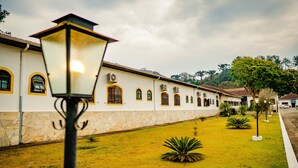 A building with a stone facade and arched windows, surrounded by a well-maintained lawn and a street lamp. - Hotel Fazenda Ramon (Sao Lourenco)