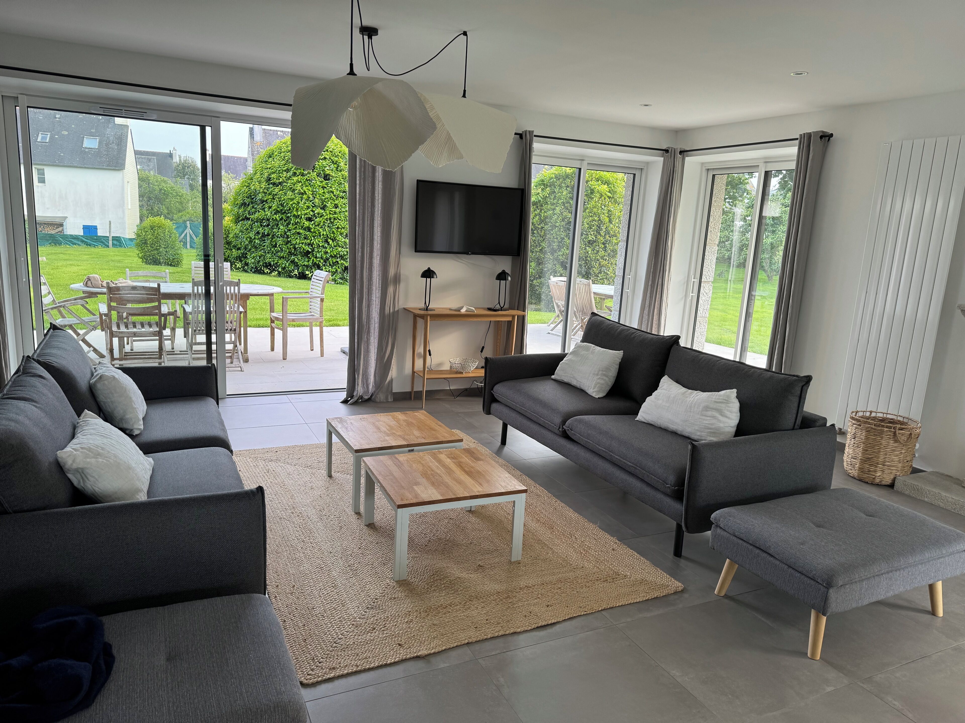 Ein modernes Wohnzimmer mit Sofa, Hocker, Couchtisch und Fernseher.