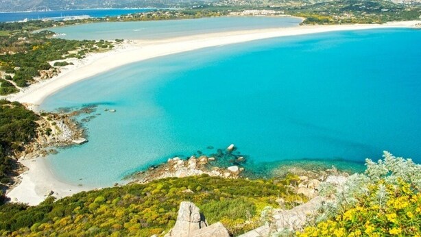 A coastal landscape with a sandy beach, clear turquoise waters, and a mountainous backdrop. - Arc Home - The charm of living in the heart of Castello, the oldest neighborhood. (Cagliari)