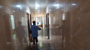 A hallway with marble floors and walls, leading to a room with a bed and a window. - Hotel Rathnavel Towers (Chennai)