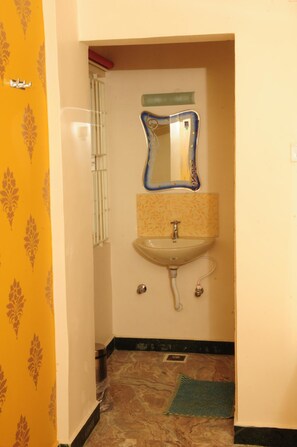 A bathroom with a sink, mirror, and patterned wallpaper. - Hotel Rathnavel Towers (Chennai)