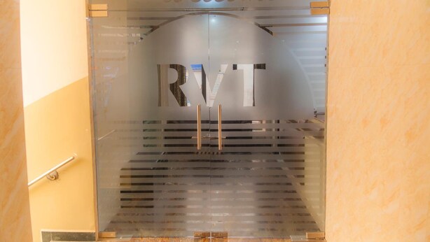 A reception area with a glass door featuring the letters "RVT" and a "Welcome" sign above it. - Hotel Rathnavel Towers (Chennai)