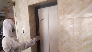 A person in a protective suit painting a door. - Hotel Rathnavel Towers (Chennai)