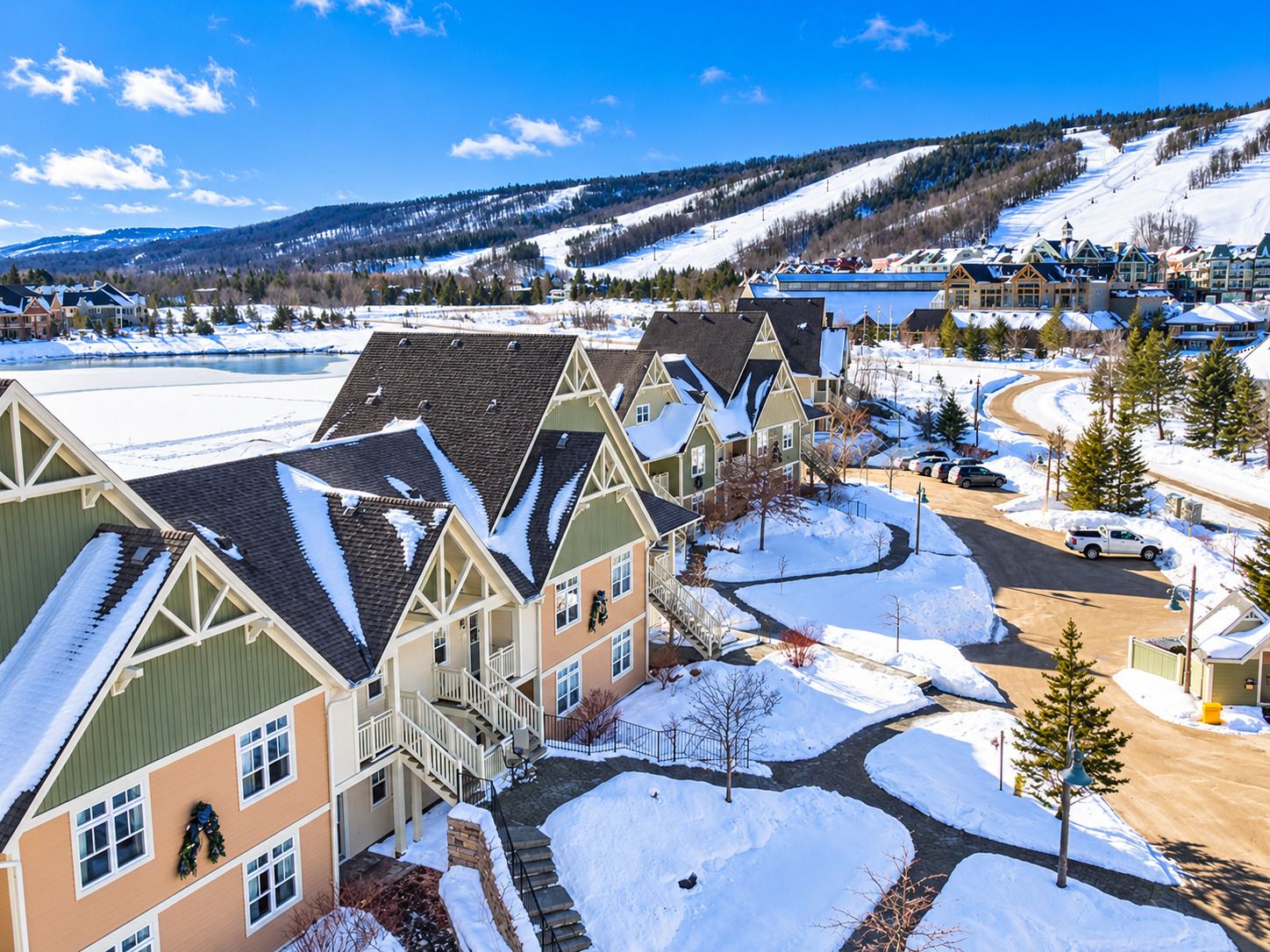 A residential area with snow-covered roofs and a clear view of a ski slope in the background.