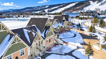 A residential area with snow-covered roofs and a clear view of a ski slope in the background.