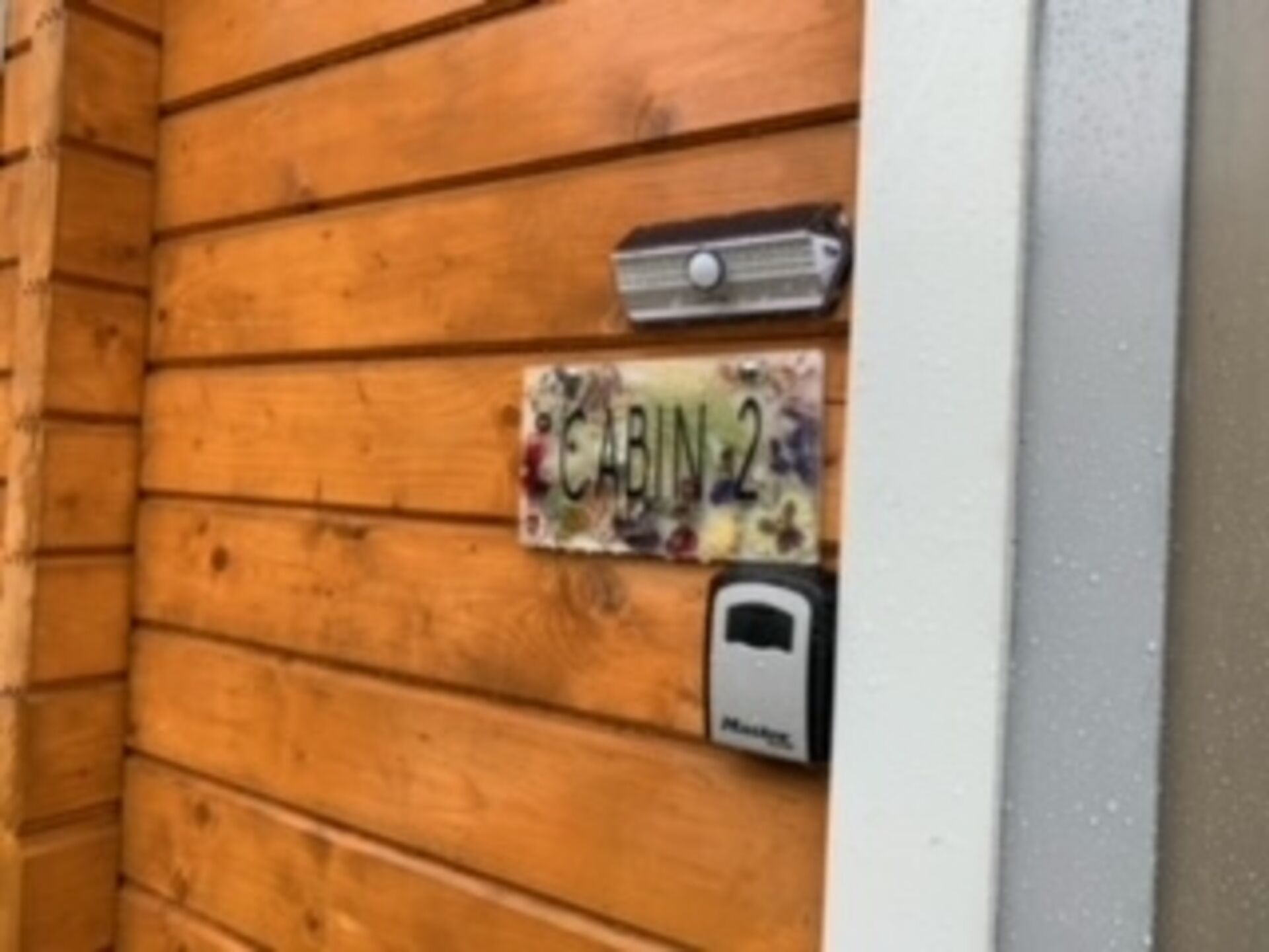 A wooden cabin wall with a sign reading "CABIN 2" and a mailbox.