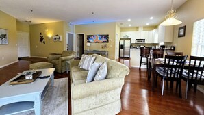 A spacious living room with a sofa, coffee table, and dining area with chairs and a table. - Apartment Live Oak Landing (Inverness)