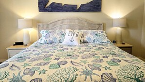 A bedroom with a bed, two bedside tables, a wall-mounted shark artwork, and a beach-themed bedspread. - Apartment Live Oak Landing (Inverness)