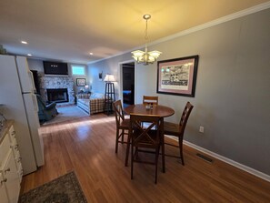A dining area with a round table and chairs, a fireplace, and a framed picture on the wall.