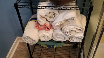 A black metal rack with folded towels, a white woven basket, and a brown bowl.