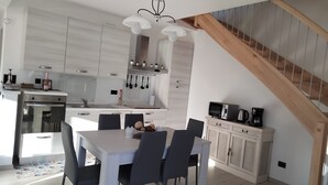Una cocina moderna con armarios blancos, una mesa de comedor con sillas y una escalera.