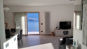 Un salón moderno con un ventanal grande, un televisor de pantalla plana y suelo de madera.