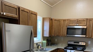 Una cocina con gabinetes de madera, un refrigerador de acero inoxidable, un microondas, un horno y un lavavajillas.