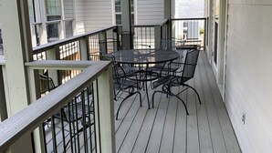 Un patio techado al aire libre con una mesa, sillas, un ventilador de techo y una baranda.