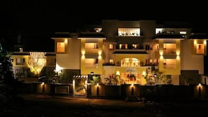 A multi-story hotel with a central entrance, balconies, and a well-lit facade. - Emerald Dove (Tirupattur)