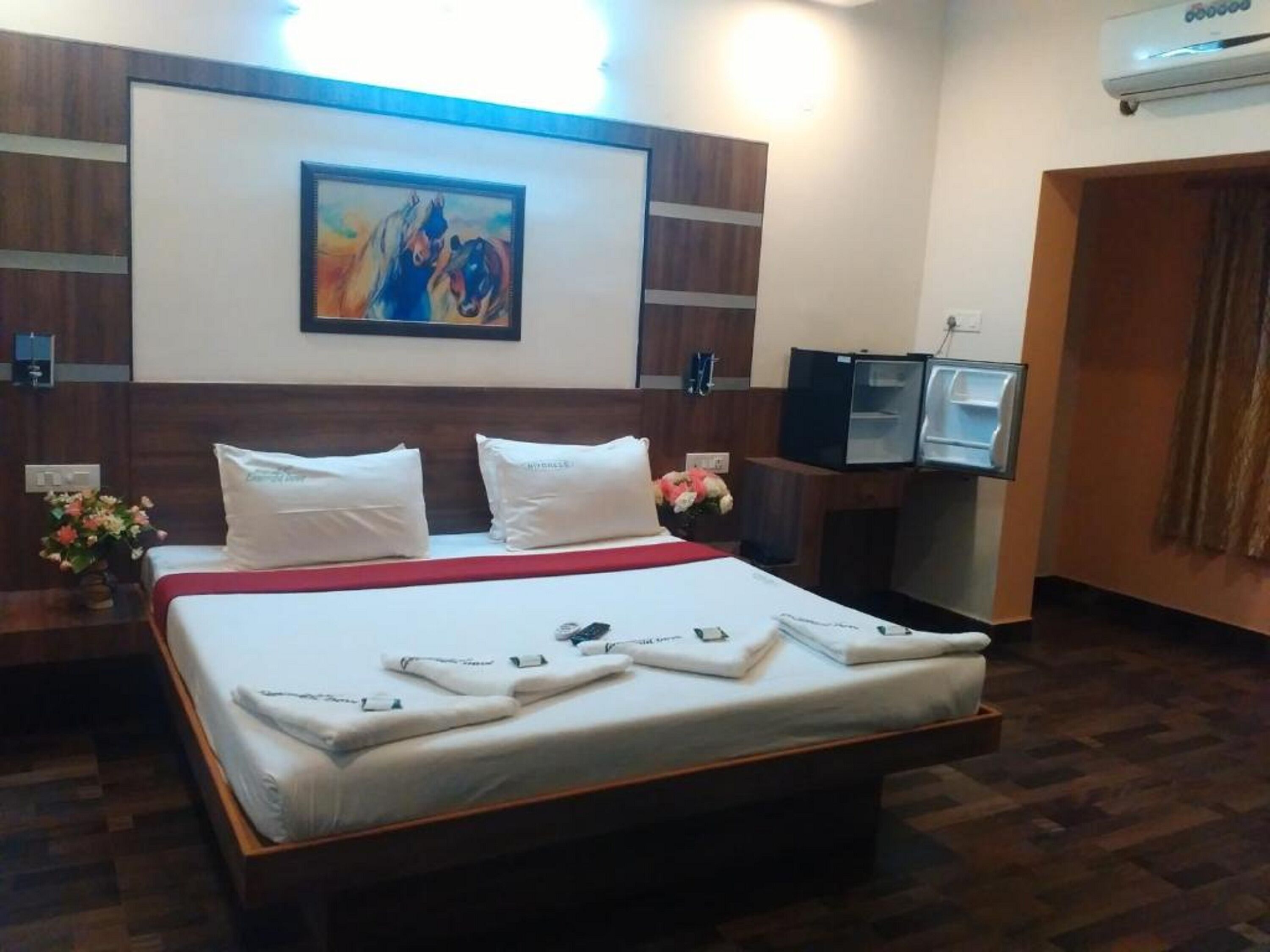 Habitación de hotel con una cama grande, un cuadro en la pared, un escritorio con computadora y un minibar.