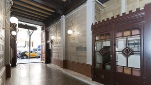 A hallway with a wooden floor, a large ornate door with glass panels, and wall-mounted light fixtures. - New apartment in the Center, Eixample Best Area! 2 minutes to Passeig de Gracia  (Barcelona)