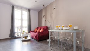 A modern living room with a dining table, clear chairs, a red sofa, and a view of the outside balcony. - New apartment in the Center, Eixample Best Area! 2 minutes to Passeig de Gracia  (Barcelona)