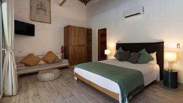 Un dormitorio con cama, lámparas de noche, un armario de madera, televisor y aire acondicionado instalado en la pared.