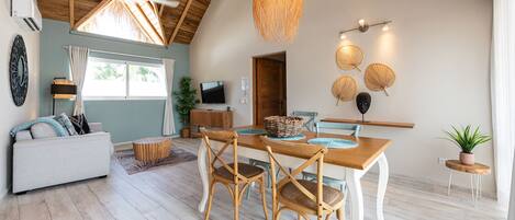A dining area with a wooden table, wicker chairs, and a hanging light fixture.