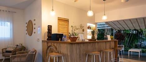 A bar area with wooden bar stools, a counter with a menu, and hanging lights.