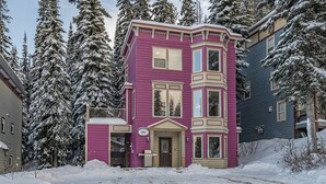 A multi-story building with a prominent pink facade, large windows, and a front porch. - Family Orientated Lower Knoll Chalet All to Yourself w/Hot Tub, Laundry, BBQ (Silver Star Mountain)