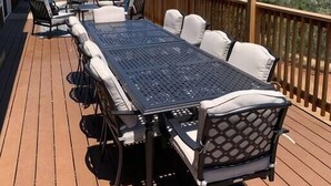 A deck with a long table and chairs, surrounded by a wooden railing, overlooking a mountainous landscape. - Villa Alta Vista at Yosemite- Mtn Views, Game Room, Pool Table, Deck, Sleeps 10+ (Mariposa County)