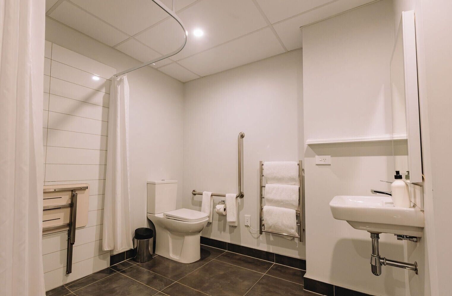 Une salle de bain moderne équipée d’un WC, d’un lavabo, d’une douche et d’un porte-serviettes.