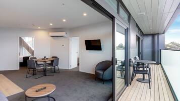 Un interior moderno con comedor, sofá y balcón con mobiliario exterior.