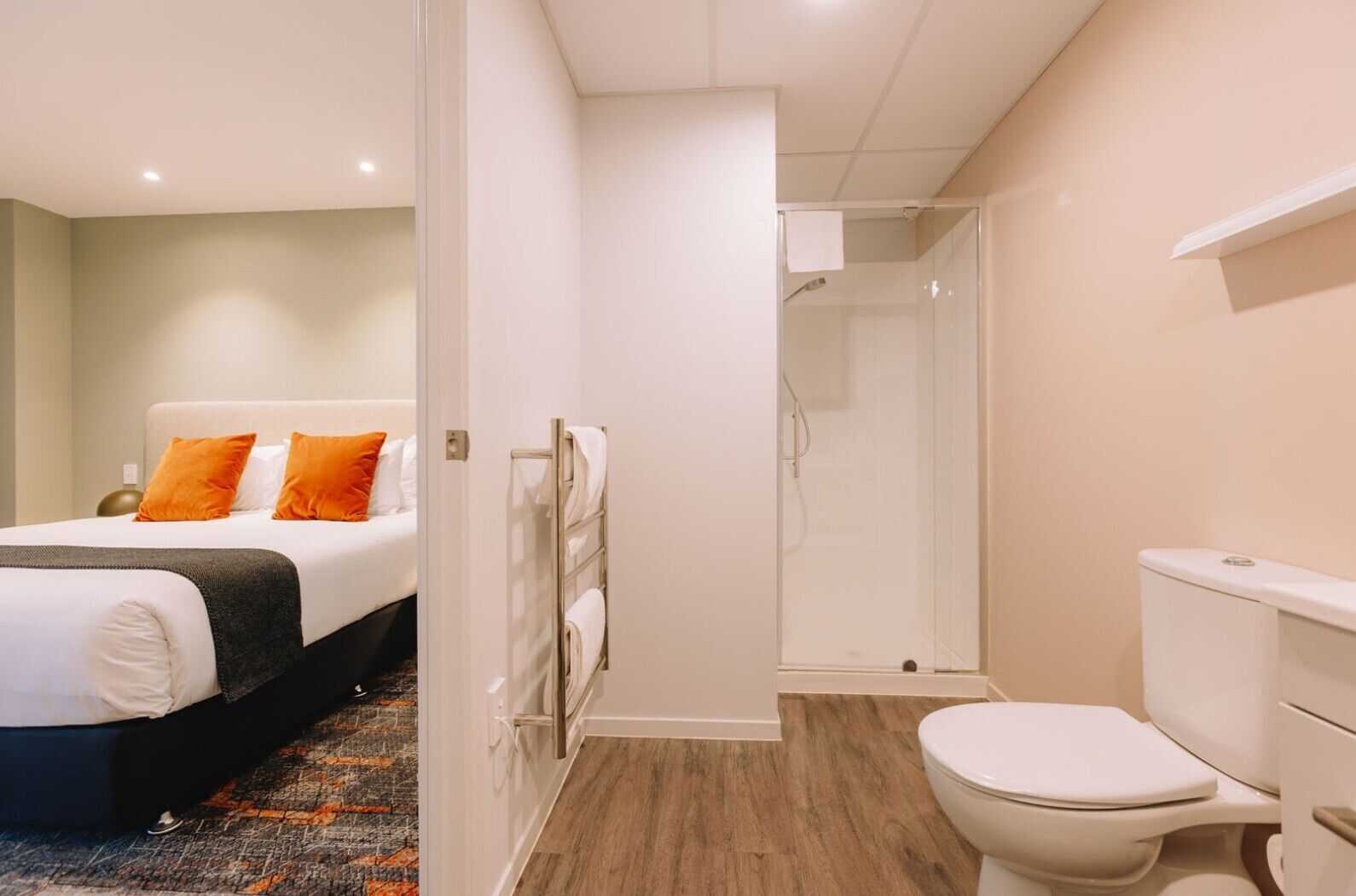A hotel room with a bed, a shower, and a toilet.