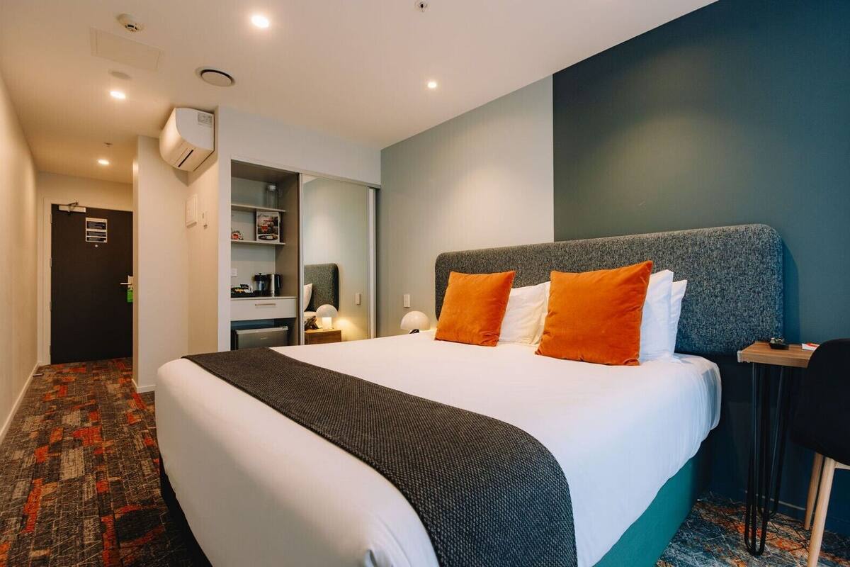 Une chambre d’hôtel avec un grand lit, une armoire, un bureau et une chaise.