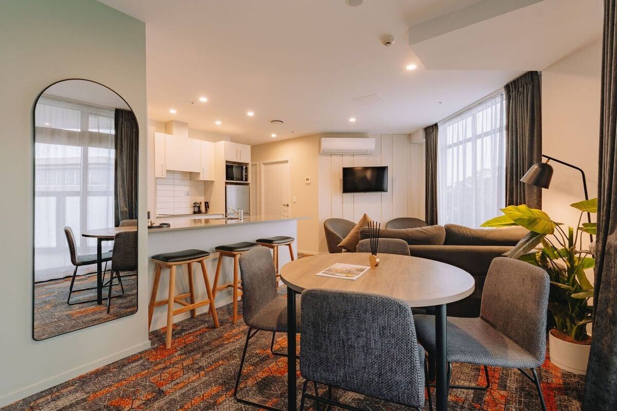 Une chambre d’hôtel moderne dotée d’un coin repas, d’une cuisine et d’un espace de vie.