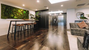 A modern interior with a dining area, bar stools, a sofa, and a large wall art piece. - Ramada by Wyndham Newmarket Auckland (Auckland)