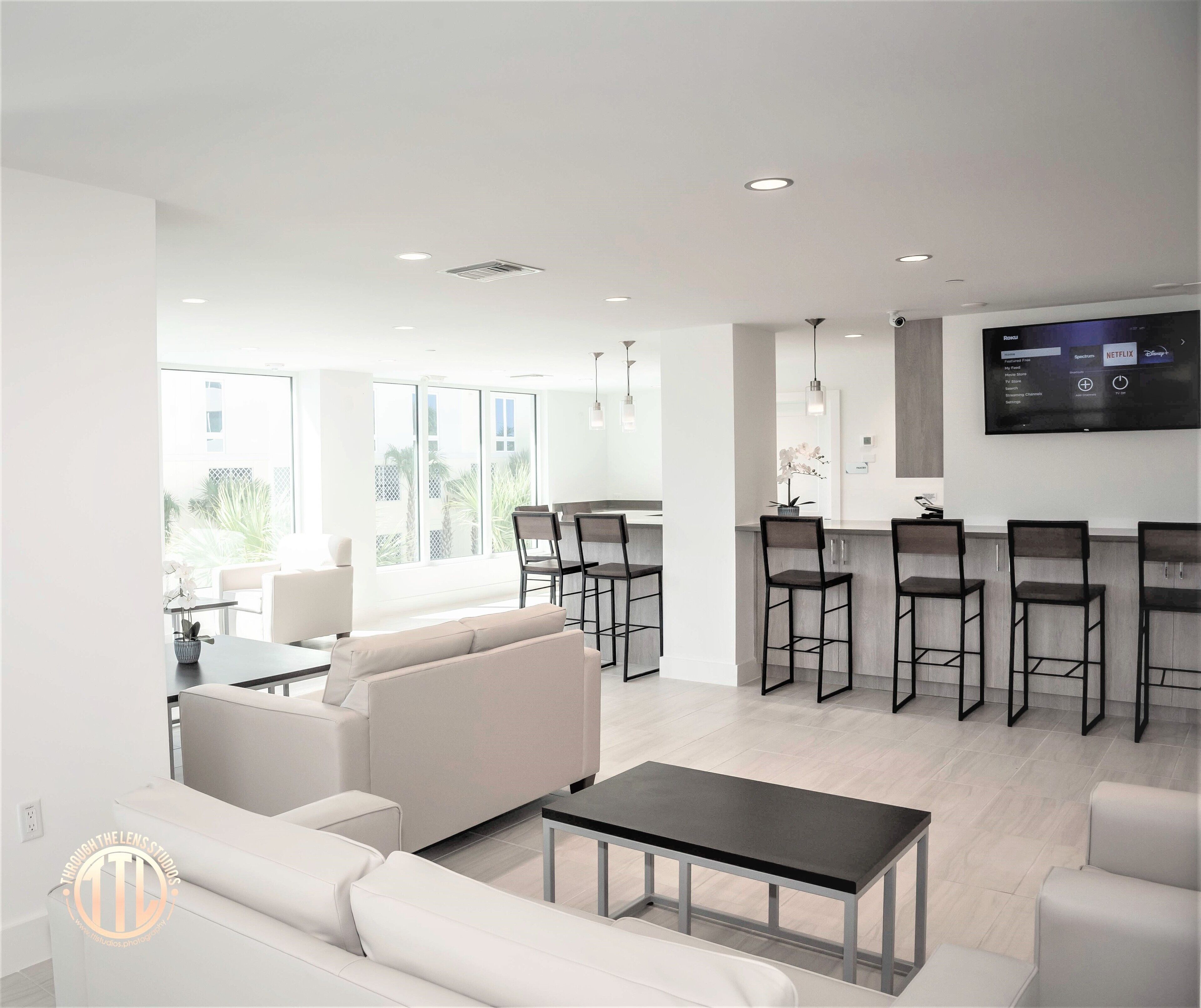 A modern living room with a sofa, a coffee table, and a kitchen area with bar stools.