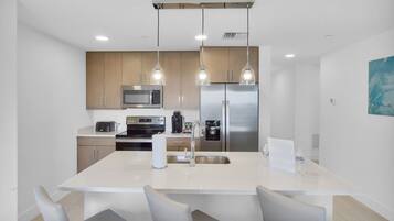 Una cocina moderna con una isla central, electrodomésticos de acero inoxidable e iluminación colgante.