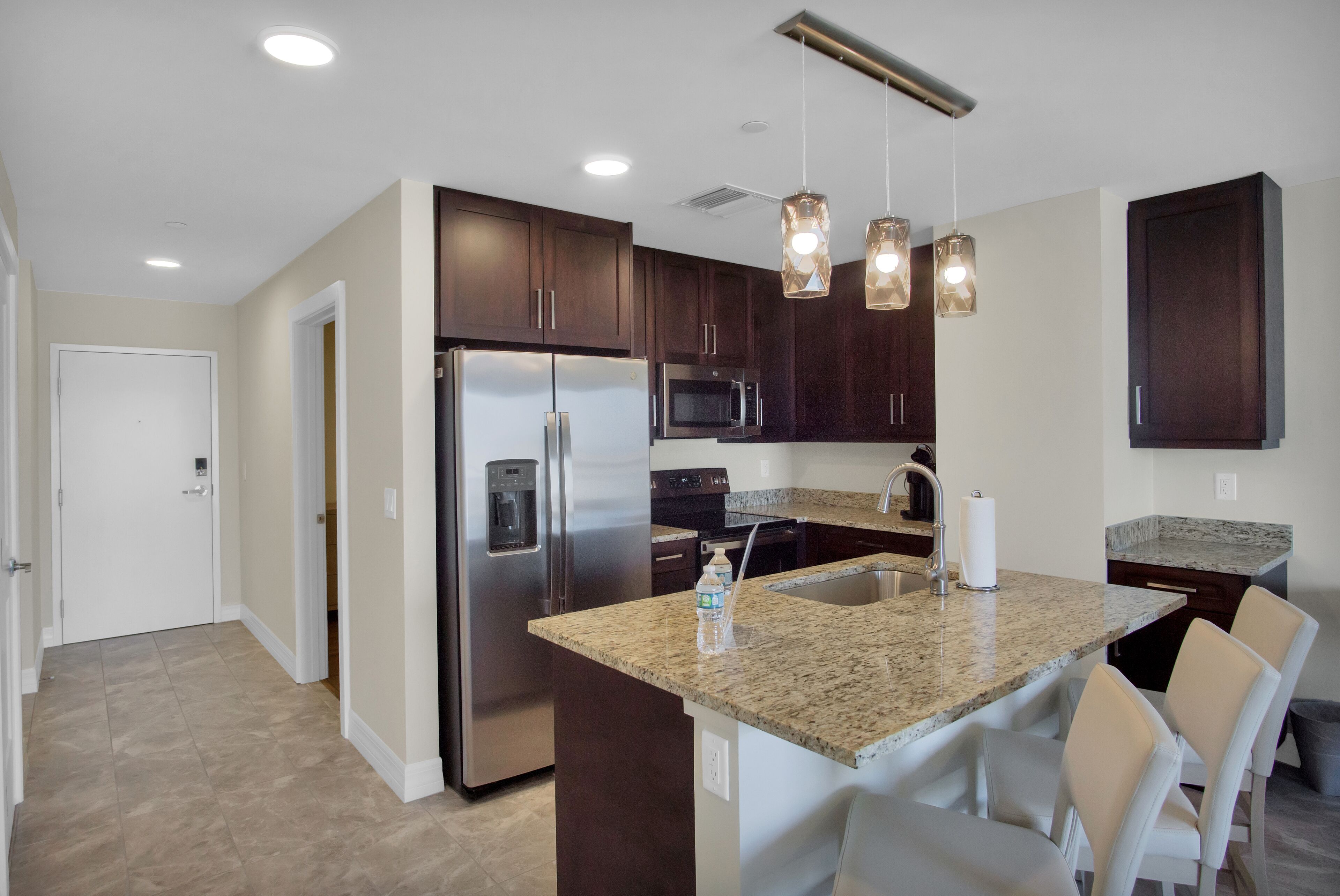 A modern kitchen with granite countertops, stainless steel appliances, and pendant lighting.