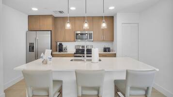 A modern kitchen with a central island, stainless steel appliances, and pendant lighting.