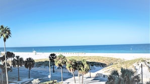 A beach with palm trees, a lifeguard tower, and a clear blue sky.