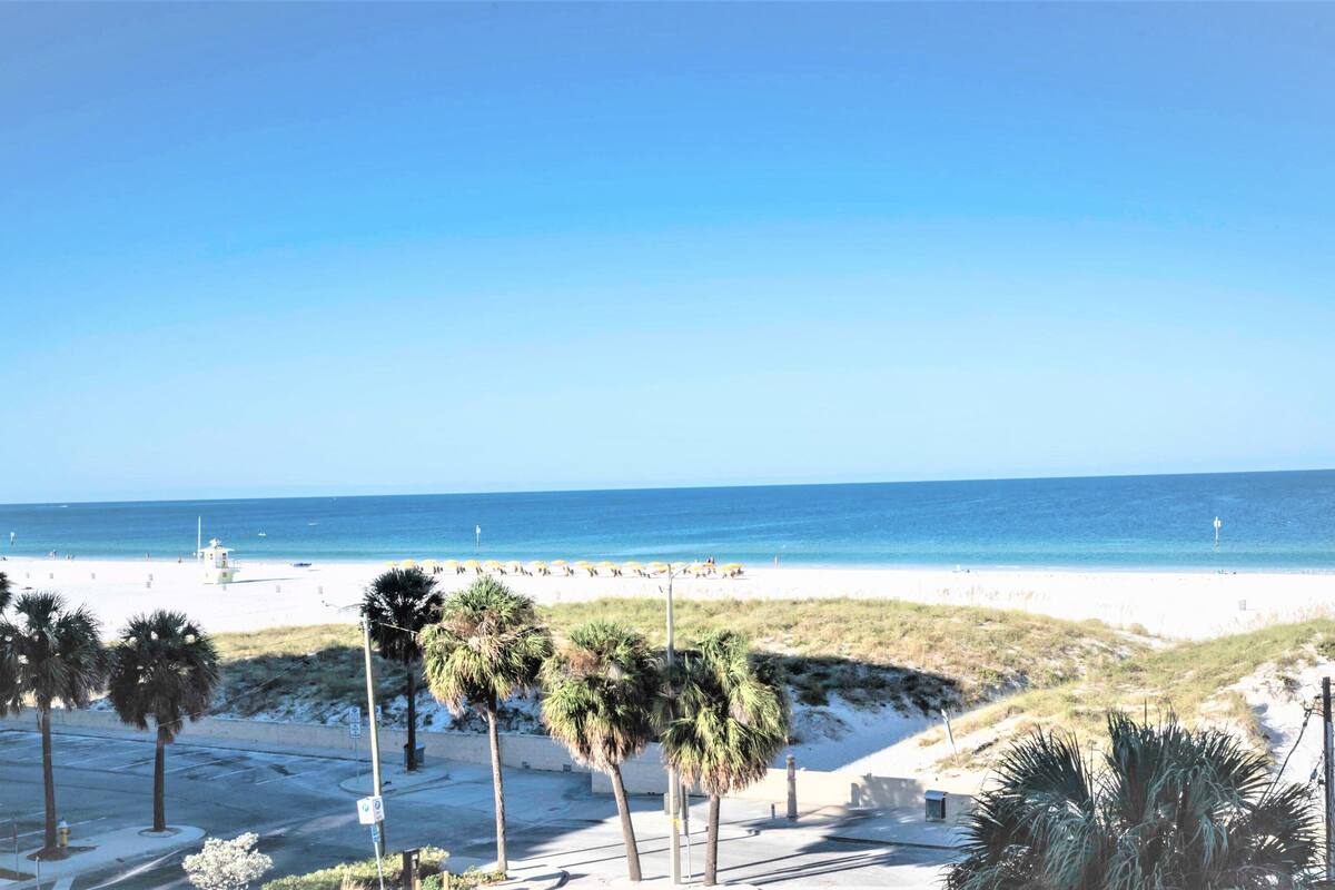 A beach with palm trees, a lifeguard tower, and a clear blue sky.