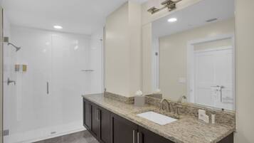 A modern bathroom with a large mirror, a sink, and a shower area.